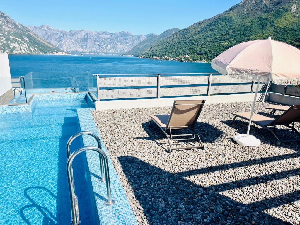 una piscina con due sedie e un ombrellone di Villa Morion a Donji Morinj