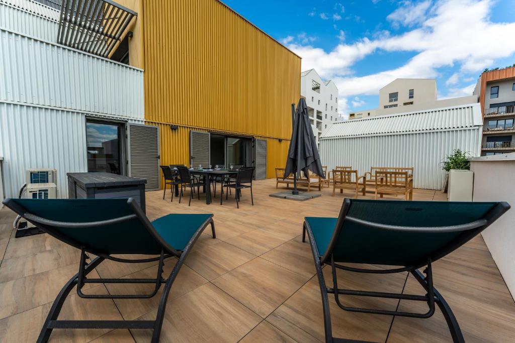 un patio avec des chaises et des tables et un mur jaune dans l'établissement Port Marianne à Montpellier avec terrasse XXL, à Montpellier