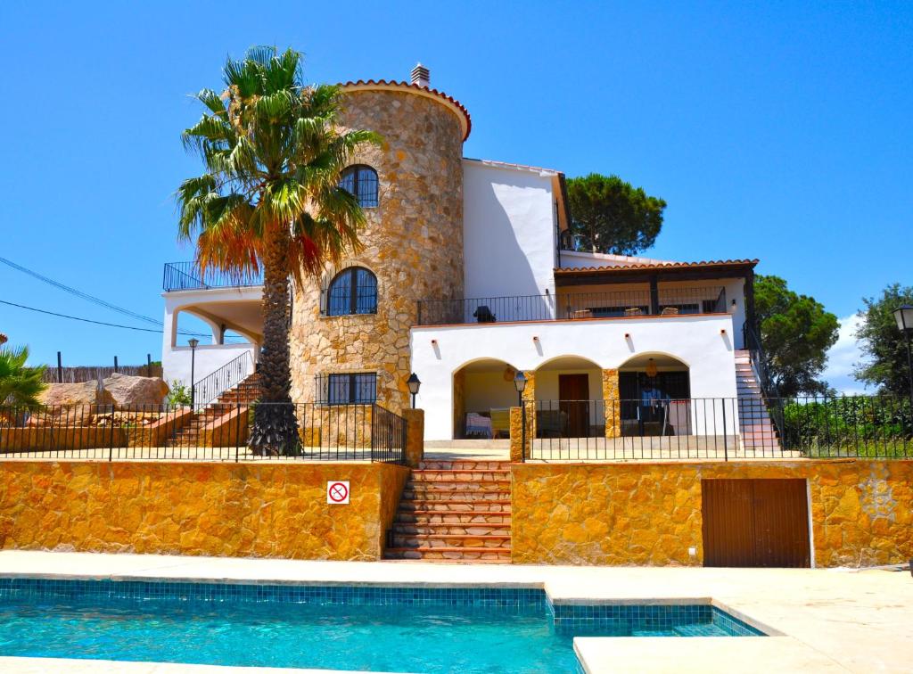 a house with a palm tree and a swimming pool at Villa Los Primos in Calonge
