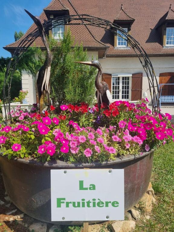 un jardin fleuri devant une maison avec deux oiseaux dans l'établissement La Fruitière, à Chaudenay
