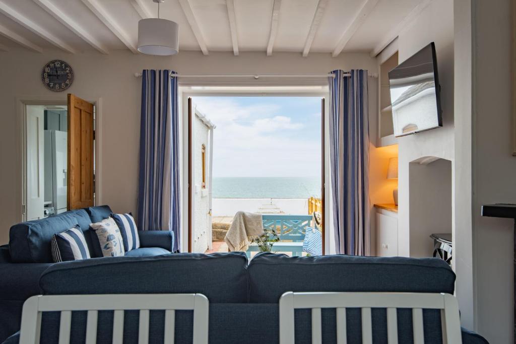 een woonkamer met een blauwe bank en uitzicht op de oceaan bij Sea Spray Cottage by Bloom Stays in Sandgate