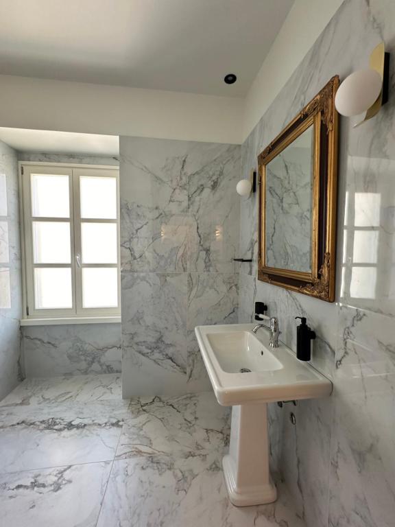 a white bathroom with a sink and a mirror at Castellano Hotel & Suites in Nafplio