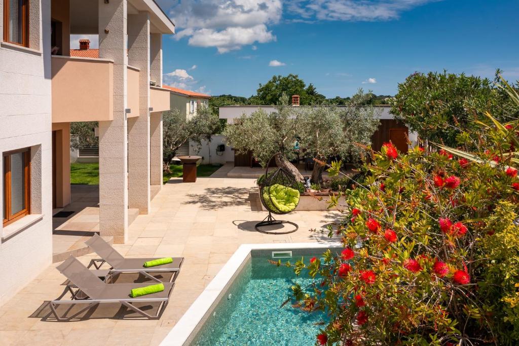 a backyard with a swimming pool and a house at Apartments Villa Pliško Wellness & Pool in Fažana