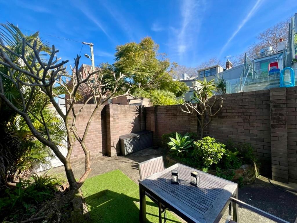 a picnic table in a garden with a brick wall at Rear Garden Suite in Sydney