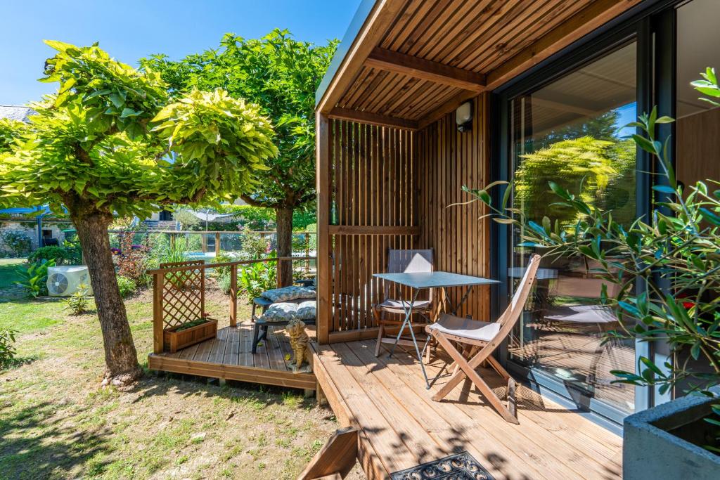 a house with a wooden deck with a table and chairs at Chambre d'hôtes de la dame blanche in Borrèze