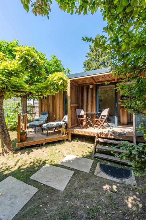 a backyard with a house with a deck and chairs at Chambre d'hôtes de la dame blanche in Borrèze