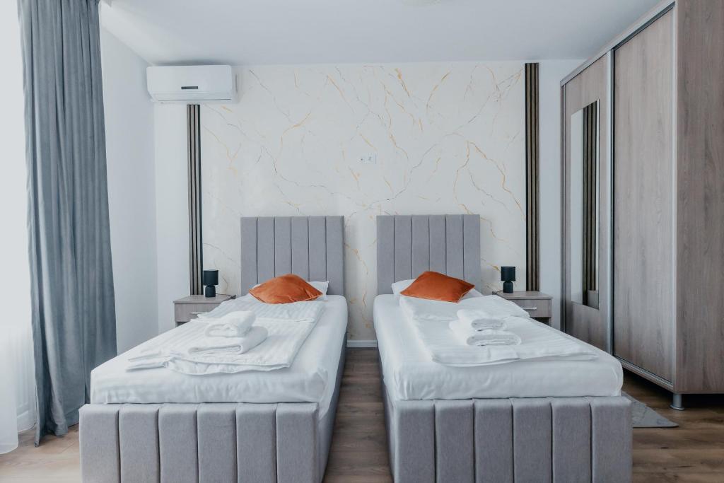 two beds in a hotel room with white sheets and orange pillows at Aparthotel Plevnei2 in Cluj-Napoca