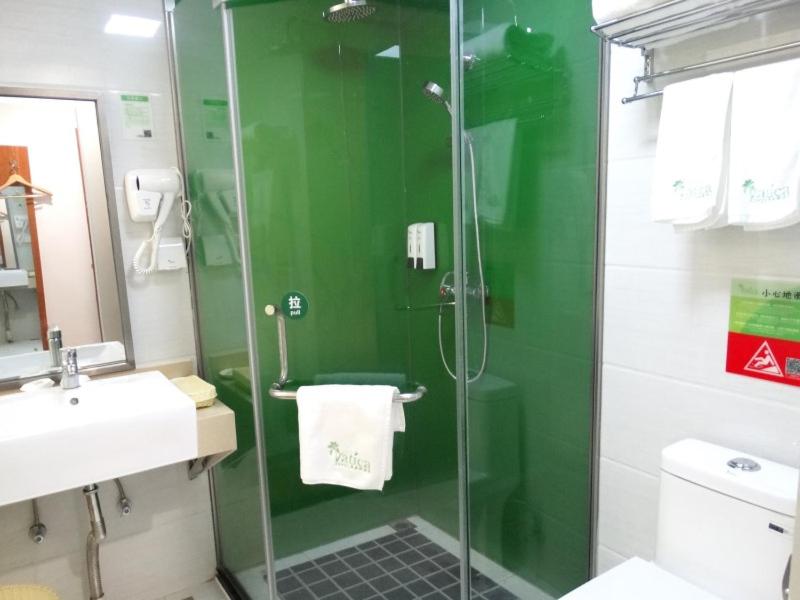 a green bathroom with a shower and a sink at Vatica Jiangsu Lianyungang Haizhou District Government Zhongyin Mingdu Hotel in Lianyungang