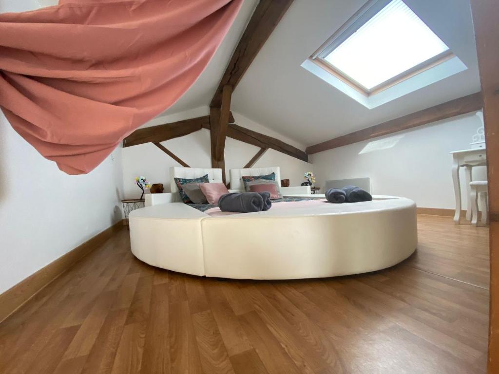 Cette chambre comprend un grand lit blanc et une lucarne. dans l'établissement My Love Room avec balnéo privative & déco romantique by BoookingFuté, à Socourt