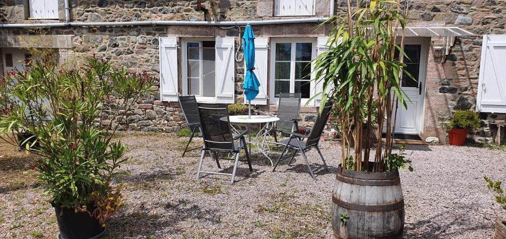 patio ze stołem, krzesłami i drzewami w obiekcie Longère à la campagne, à proximité de la mer w mieście Plurien