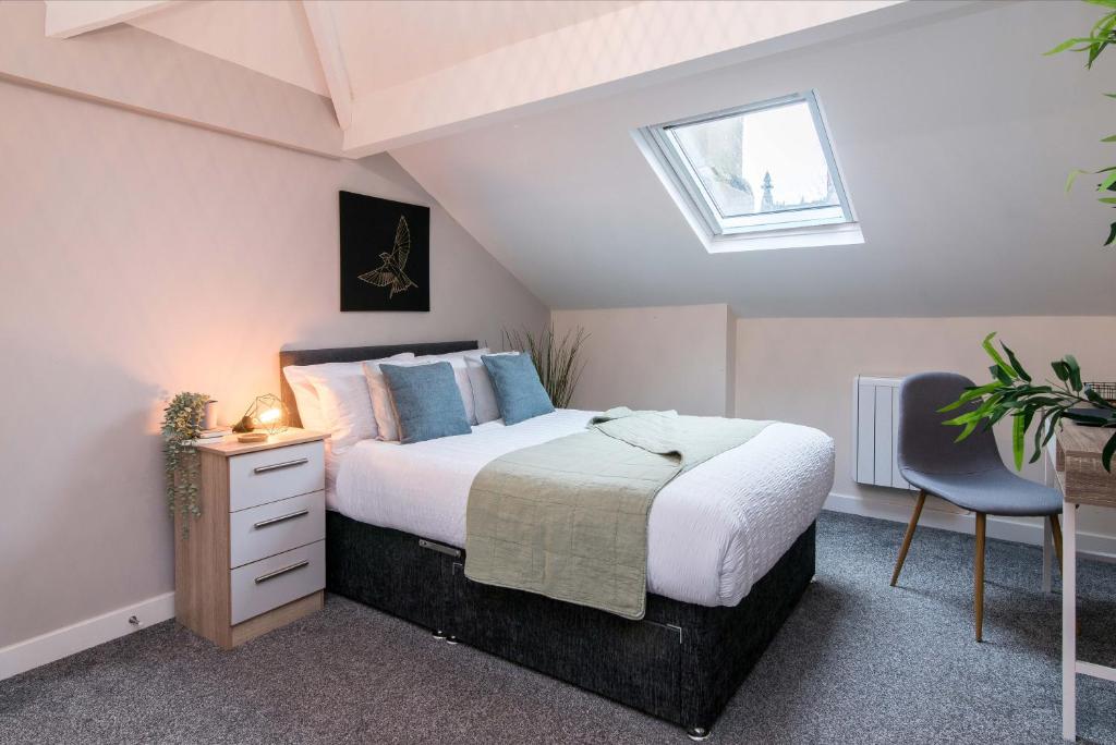 ダービーにあるcheerful double en-suite room with free wifiのベッドと机と窓のある寝室