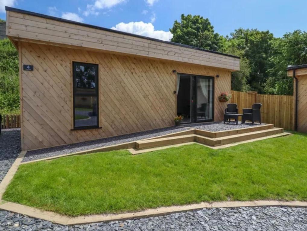 a small house with a patio and grass at North Wales Eco Lodges in Ruthin