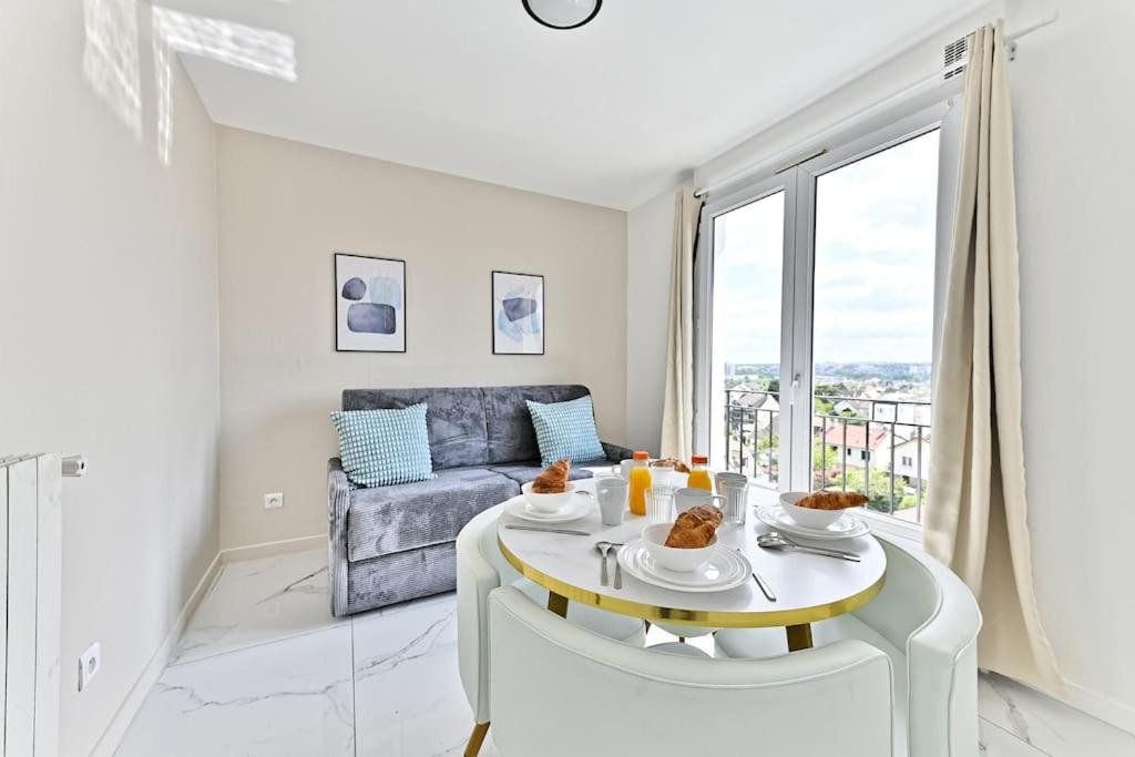 un salon blanc avec une table et un canapé dans l'établissement Appartement proche de Paris - Gagny - II, à Gagny