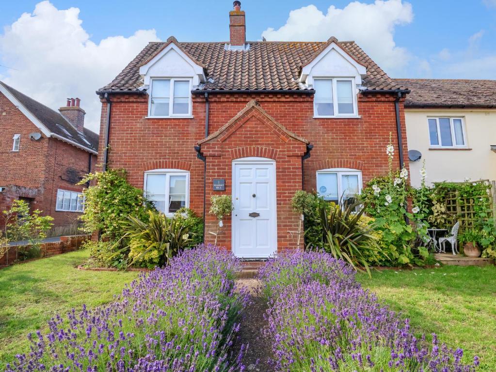 a red brick house with purple flowers in the yard at 1 Market Hill in Woodbridge
