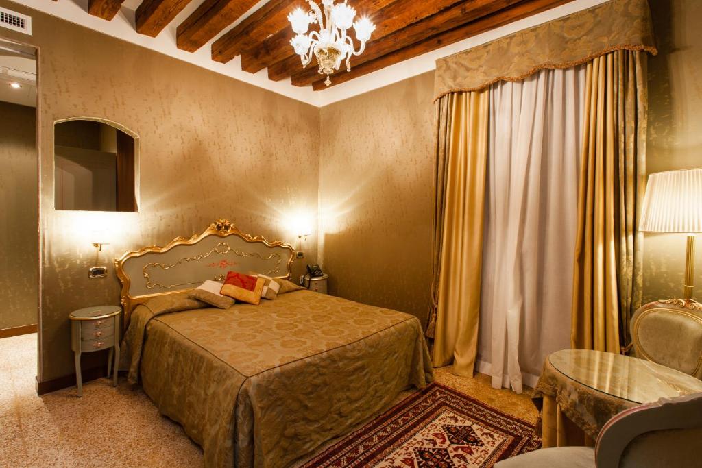 Schlafzimmer mit einem Bett und einem Kronleuchter in der Unterkunft Hotel Al Ponte Mocenigo in Venedig