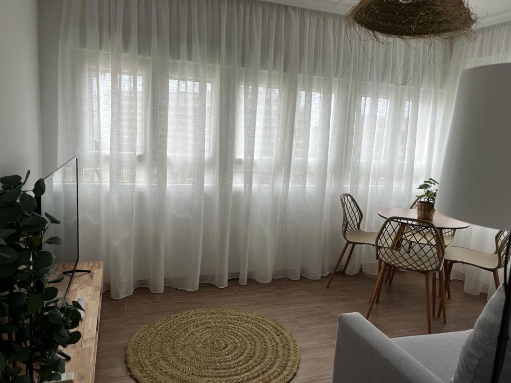 a living room with a table and a white curtain at Sea City Torremolinos Beach in Torremolinos