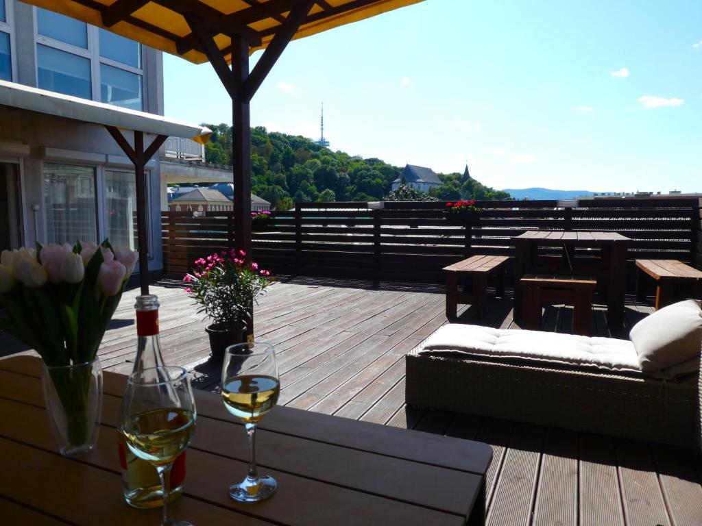 a deck with a table with wine glasses and flowers at Panoráma Apartman in Miskolc