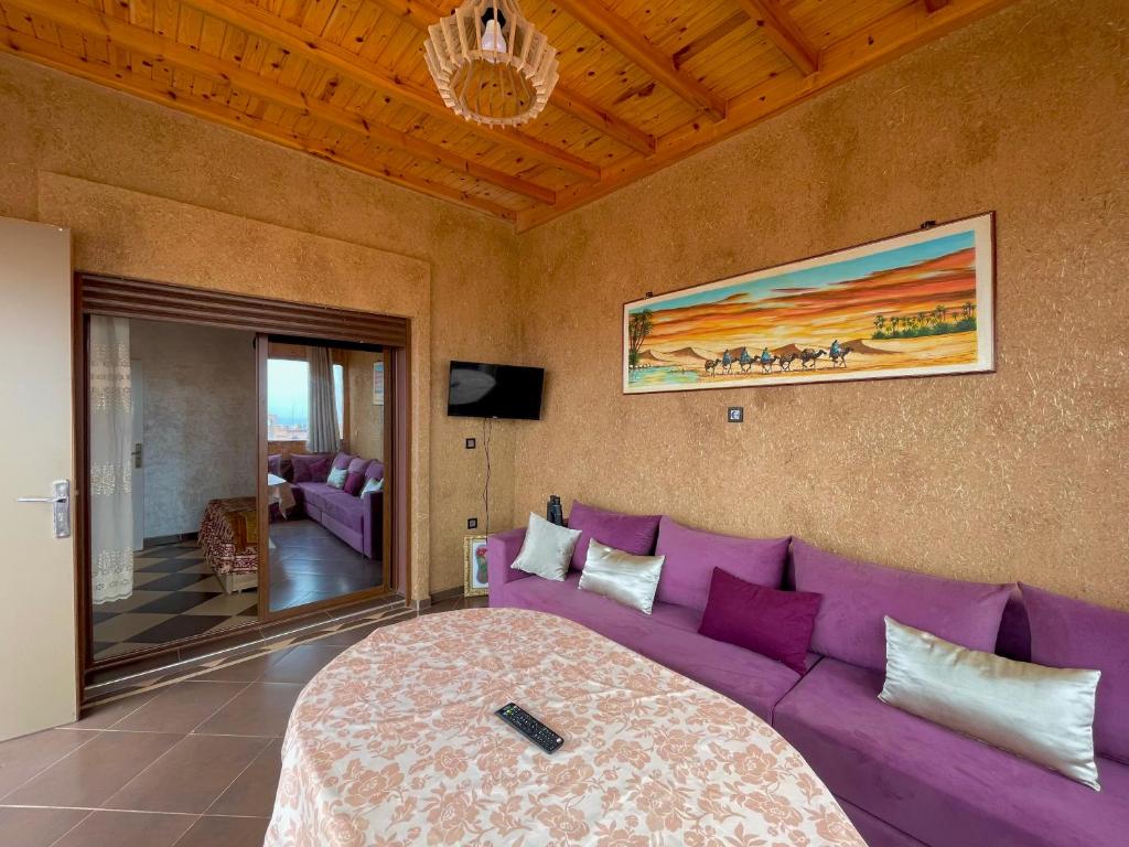 a living room with a purple couch and a tv at Petite villa palmeraie d Aglou in Tiznit