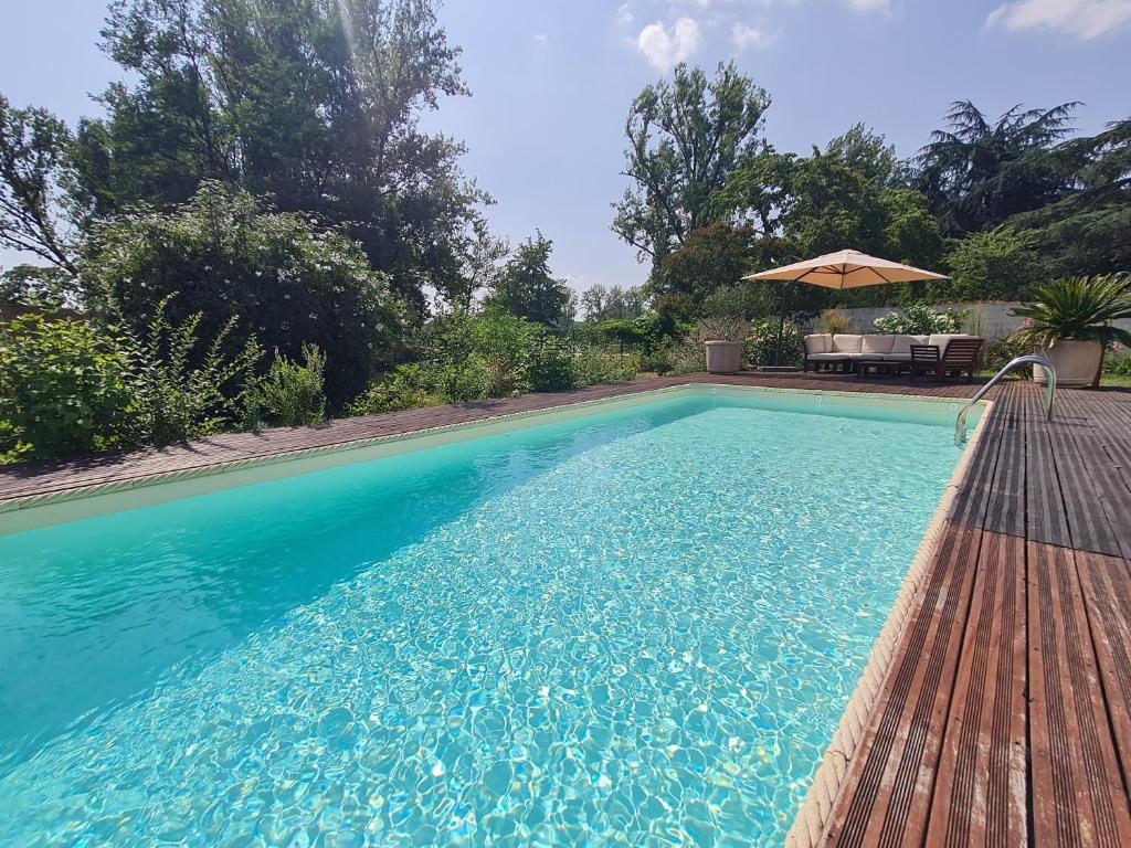 une piscine avec une table et un parasol dans l'établissement l'oasis girondine 4 étoiles, à Izon