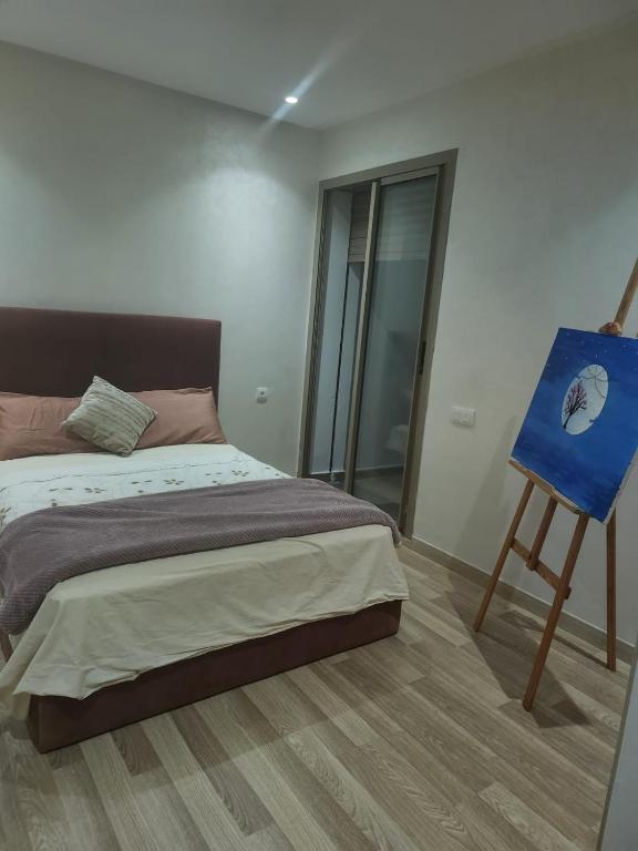 a bedroom with a bed and a blue easel at Les Villas Casa del mar à sidi rahal in Sidi Rahal