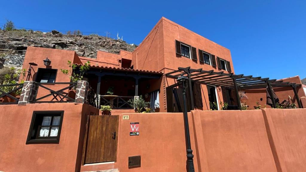 a red brick building with a fence in front of it at Casa Moni con Vistas al Mar in Playa de Santiago