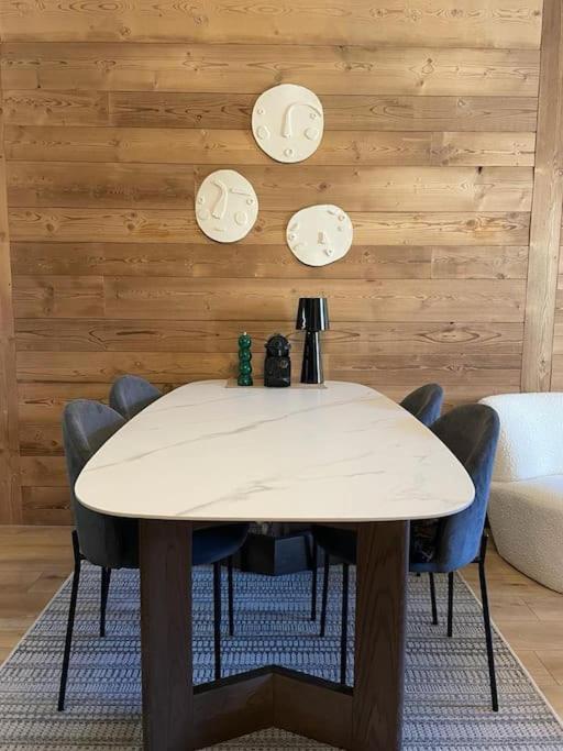 une table blanche avec des chaises et des horloges sur un mur dans l'établissement Beautiful central 2 bedrooms apartment in Auron, à Saint-Étienne-de-Tinée