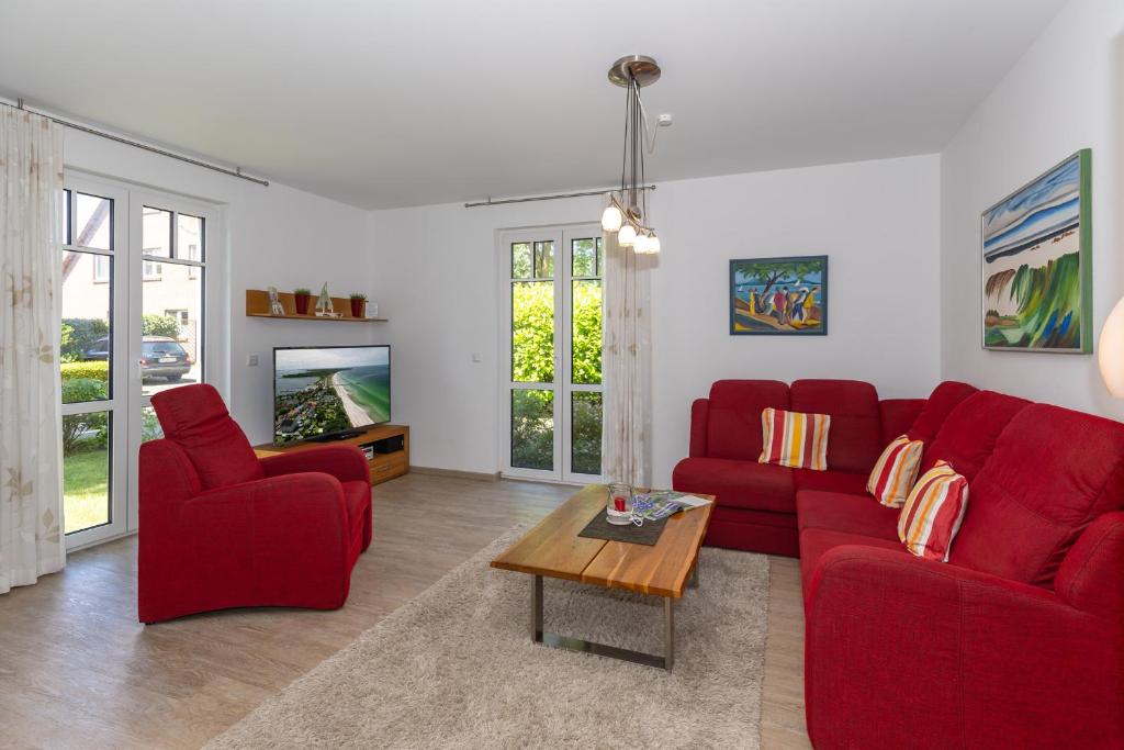 a living room with red couches and a tv at Strandvilla Luv Lee Miramar in Rerik