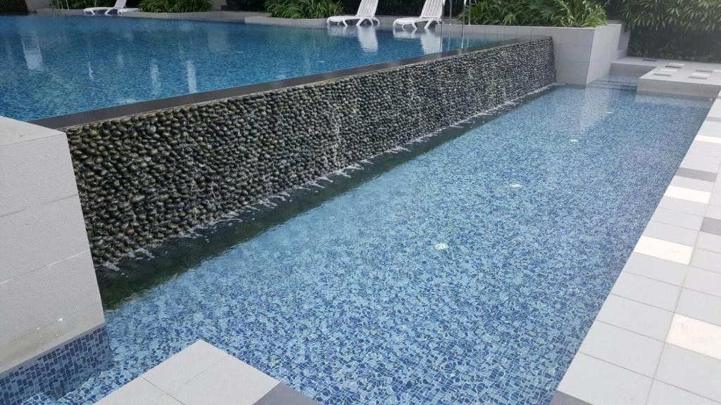 a swimming pool with blue gravel and a retaining wall at Seth Vacationstay Shah Alam in Shah Alam