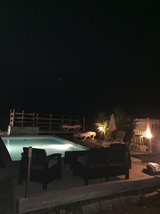 - une piscine de nuit avec des chaises et des tables dans l'établissement Maison avec piscine, à Alata