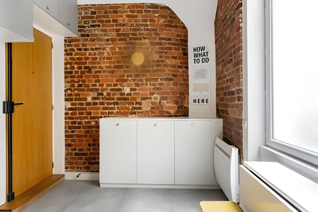 Cette chambre est dotée d'un mur en briques et d'une armoire blanche. dans l'établissement Casa Naranja, à Paris