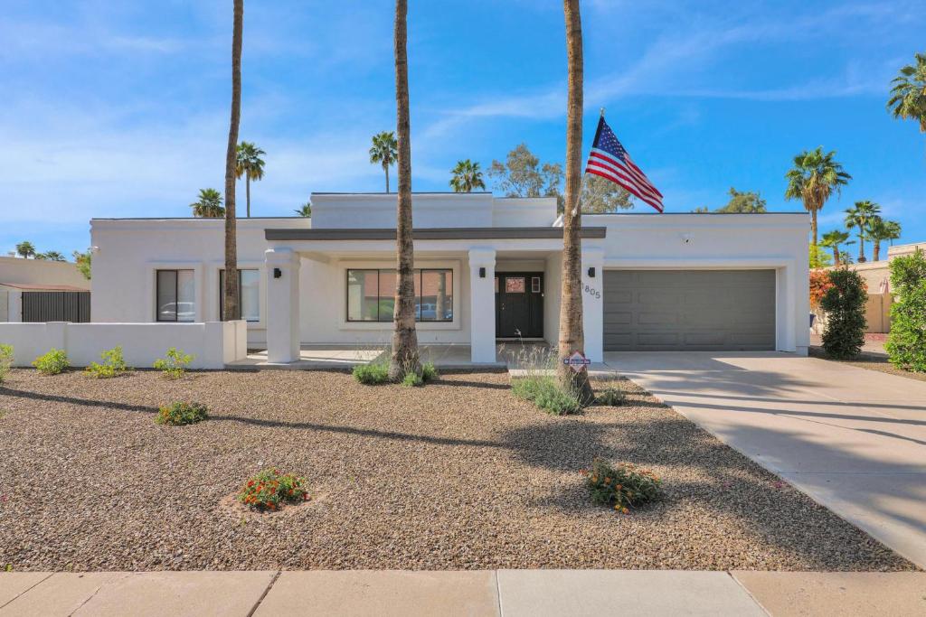 a white house with palm trees and an american flag at Sunlit Serenity in Tempe in Tempe
