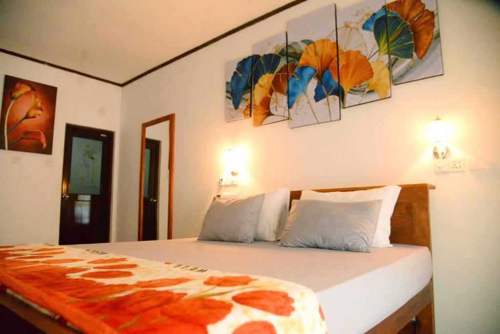 a bedroom with a bed with paintings on the wall at Okeed Ella in Ella