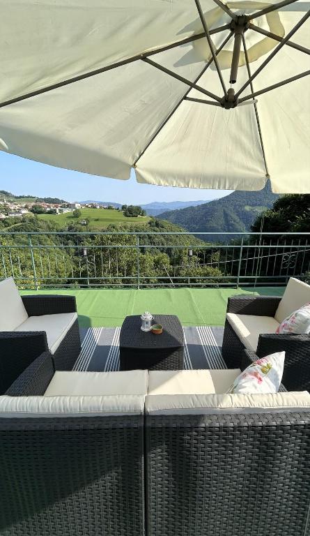 a patio with white chairs and an umbrella at B&B Baldì in Pertica Alta