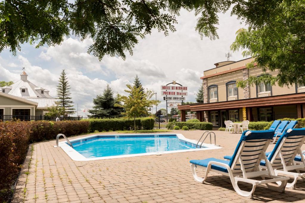 two chairs and a swimming pool in a yard at Hôtel St-Bernard in St-Bernard de Lacolle