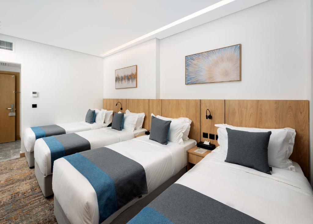 a row of three beds in a hotel room at فندق السعفة الذهبية Assaafa Golden Hotel in Al Madinah