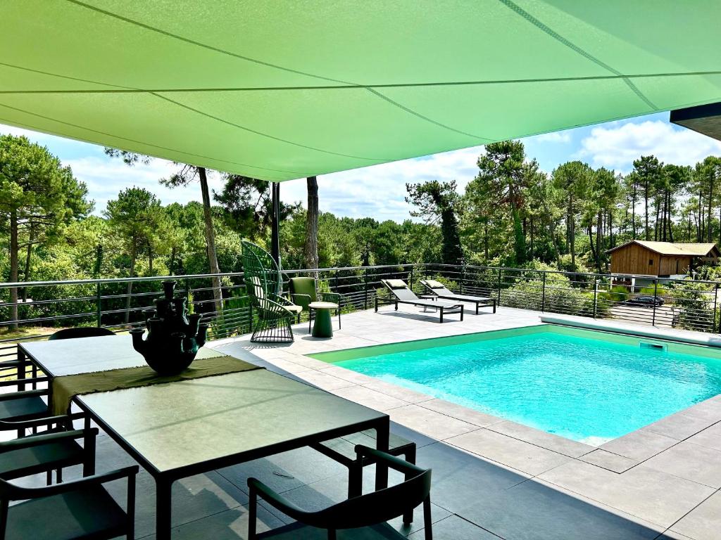 eine Terrasse mit Tisch und Swimmingpool in der Unterkunft MAISON CHAPRON Villa de standing avec piscine, calme et golf à Biscarrosse in Biscarrosse