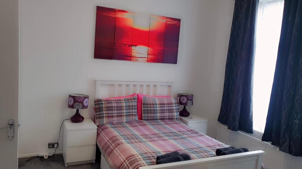 a small bedroom with a bed and two windows at 2 bed 1st floor Apartment-own entrance & parking in Portsmouth