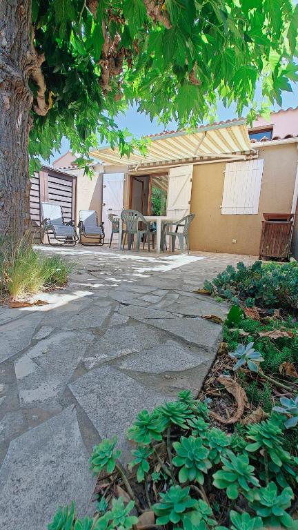 un patio avec une table et des chaises sous un arbre dans l'établissement pavillon 40m2, 2 Chambres, 1 salon cuisine, 1sdb, à Gruissan