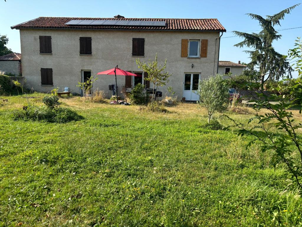 a house with a red umbrella in a field at Chez Benoit, séjour Zen, chambre d'amis in Mazerolles
