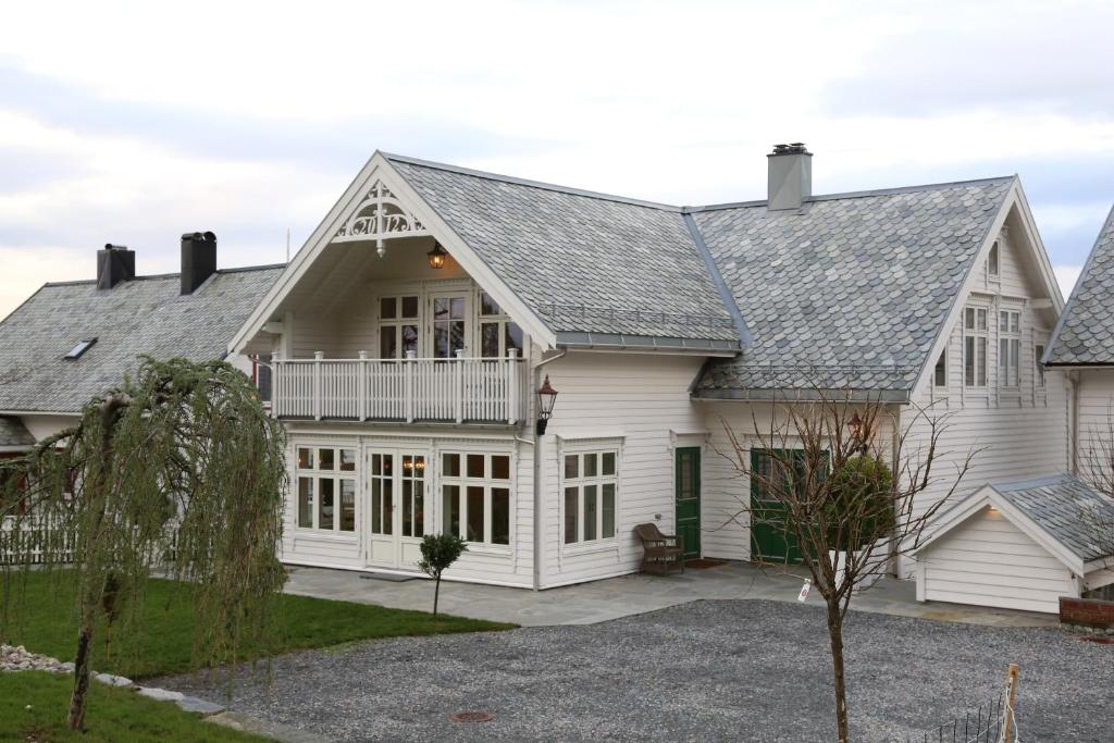 una casa blanca con techo de gambrel en Alnes Gård, en Ålesund