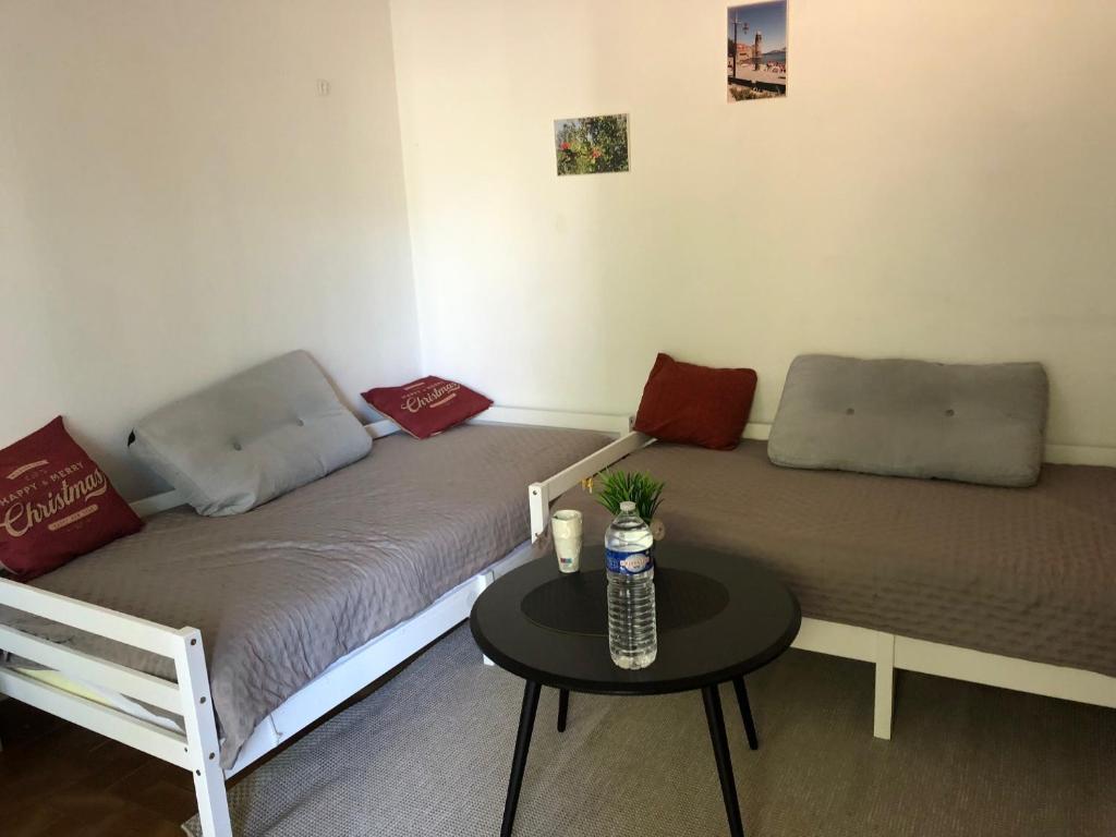 Cette chambre comprend deux lits et une petite table. dans l'établissement Studio soleil montagne et rivière, à Amélie-les-Bains-Palalda