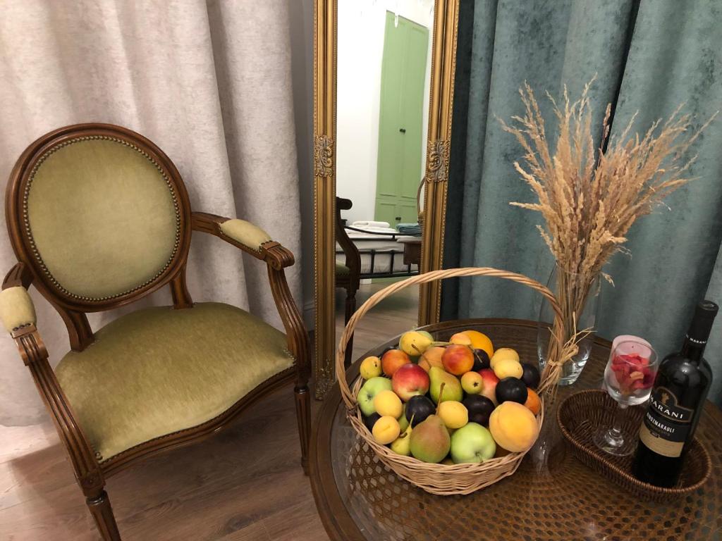 Una cesta de fruta junto a una silla y un espejo. en Apartments MARGARITA, en Tiflis