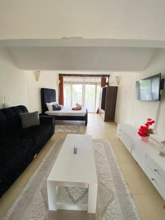 a living room with a black couch and a white table at Diani, Beach Front Studio in Ukunda