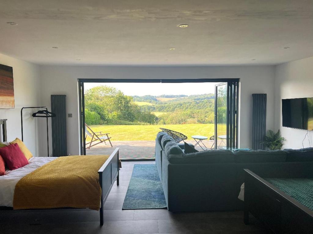 a bedroom with a couch and a bed and a sliding glass door at The Pod in Crowhurst