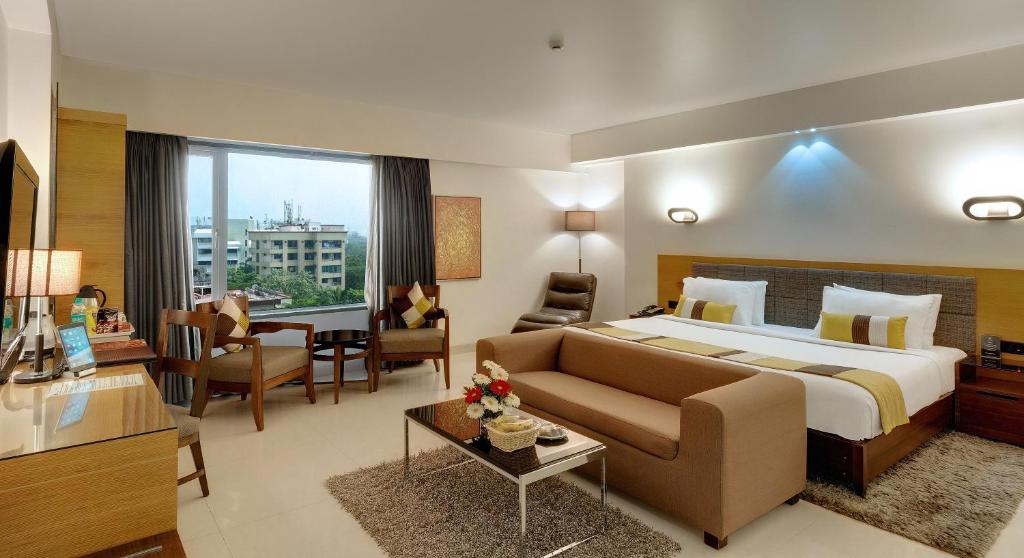 a large hotel room with a bed and a couch at Hotel Suba International in Mumbai