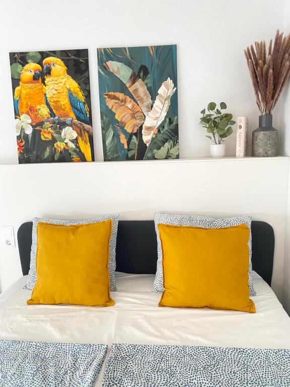 two yellow pillows on a bed with two paintings above it at Santa Banana Apartment Alicante in Alicante