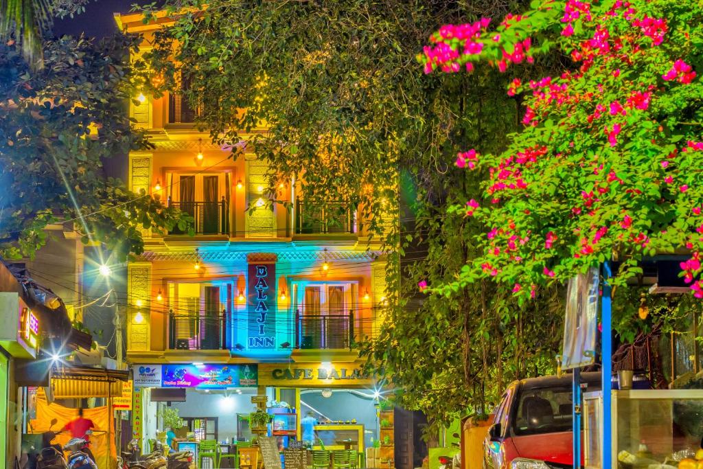 a building at night with pink flowers in front of it at Beach Comforts By Balaji Inn in Calangute
