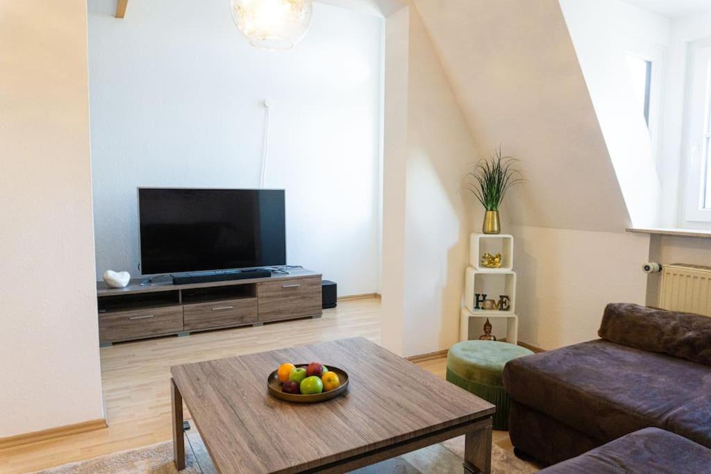 a living room with a television and a bowl of fruit on a table at Casa Burgplatz - Maisonettewohnung in Hüfingen