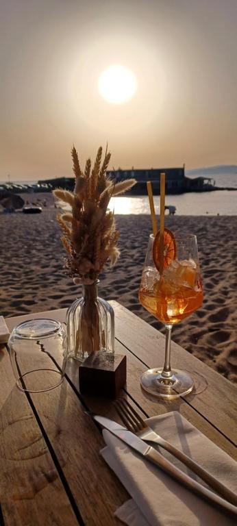 une table avec une boisson et un vase de fleurs sur la plage dans l'établissement face à la mer, à Propriano