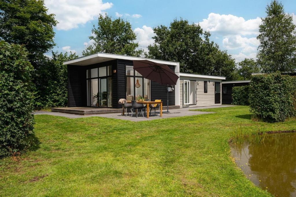 een klein huis met een tafel en een paraplu bij Vakantiepark Hölte in Rijssen